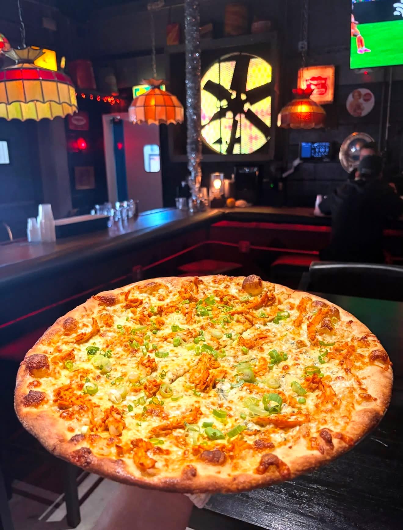Buffalo chicken pizza in the dark lounge, stained glass lamps overhead